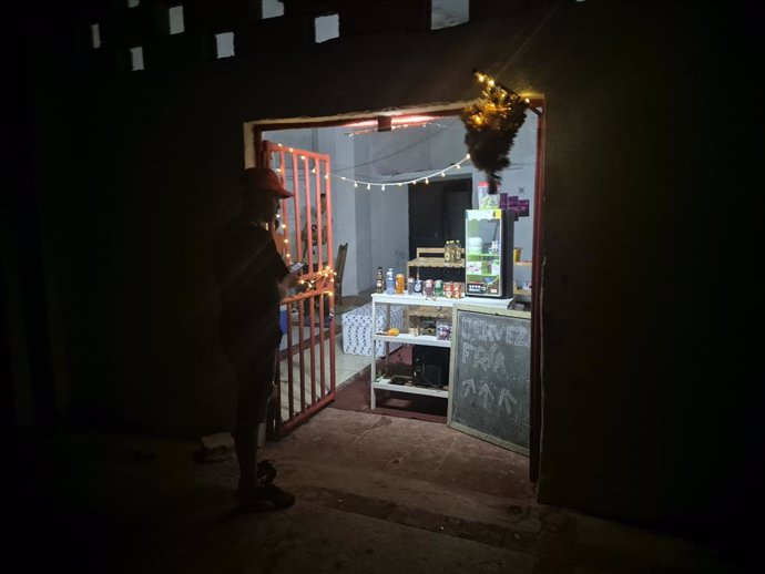 Archivo - 20 October 2024, Cuba, Havana: A man stands in front of a store that has electricity and advertises cold beer during a blackout in Havana, following the failure of a major power plant. Hurricane Oscar on Sunday evening made landfall in Cuba, whe