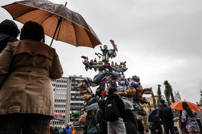 Varias personas con paraguas durante el montaje de la Falla del Ayuntamiento, a 14 de marzo de 2025, en Valencia, Comunidad Valenciana (España). Los monumentos falleros de este año han supuesto una inversión de 9,2 millones de euros y están marcados por l