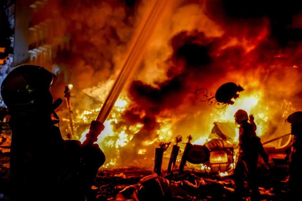 Archivo - Un bombero echando agua con una manguera,  en una falla quemándose, durante la Cremá, a 19 de marzo de 2022, en Valencia
