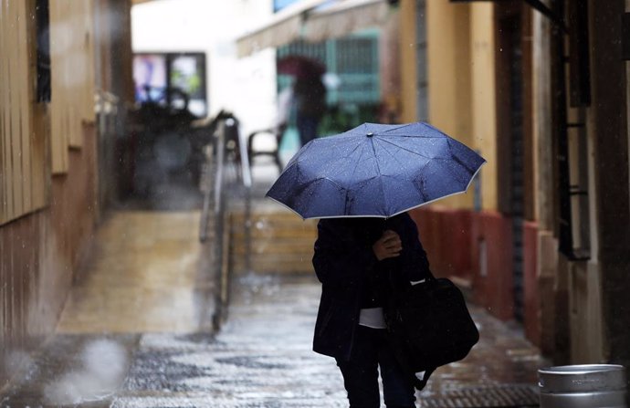 Una persona se protege de la lluvia en Málaga. A 13 de marzo de 2025, en Málaga (Andalucía, España). (Foto de archivo).