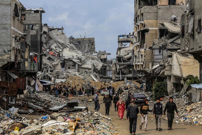 Archivo - Arquivo - Palestinos passam por prédios destruídos na cidade de Khan Younis, no sul do país, pela ofensiva do exército israelense contra a Faixa de Gaza (arquivo).