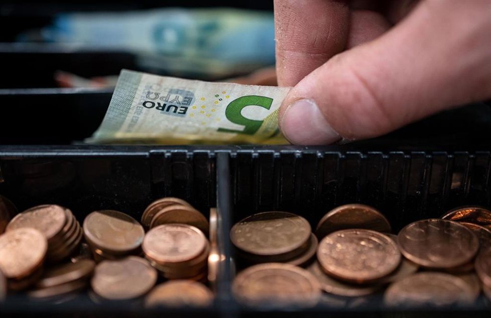 Archivo - FILED - 30 March 2022, Baden-Wuerttemberg, Stuttgart: An employee of a retail store takes a 5-euro bill from a checkout.  