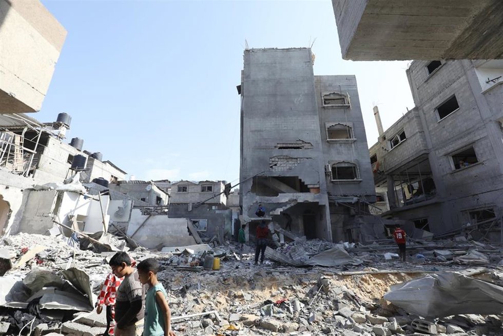 Civiles palestinos junto a escombros de edificios destruidos en Nuseirat, en la Franja de Gaza