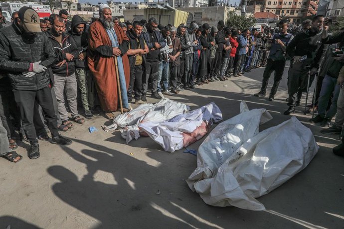 ARQUIVADO - 18 de março de 2025, Territórios Palestinos, Khan Yunis: Palestinos rezam sobre os corpos cobertos daqueles que foram mortos nos ataques aéreos israelenses em Khan Yunis. Israel lançou uma série de ataques aéreos contra o grupo islâmico palest