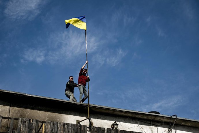 9 de março de 2025, Zaporizhzhia, Ucrânia: Hennadii Vovchenko, um dos fundadores do Centro de Voluntários de Palianytsia, instala uma bandeira ucraniana no telhado de uma oficina do centro destruída por um ataque noturno de um drone russo Shahed em 8 de m