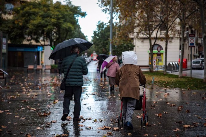 Archivo - Un home i una dona durant un dia plujós