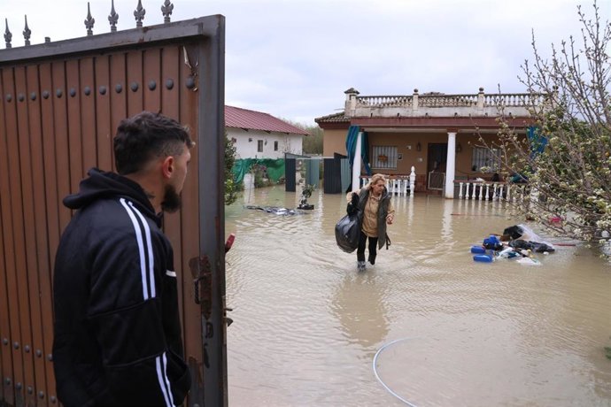 Una mujer recoge enseres de su vivienda, anegada por la crecida del río Guadalquivir a su paso por Córdoba capital.