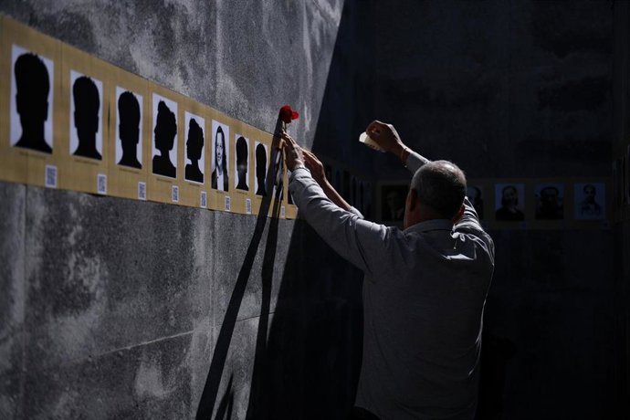 Archivo - Un hombre coloca un clavel en la foto de una víctima durante el XVII Homenaje a las víctimas del franquismo en Madrid, de Memoria y Libertad, en el Cementerio del Este, a 15 de abril de 2023, en Madrid (España). 