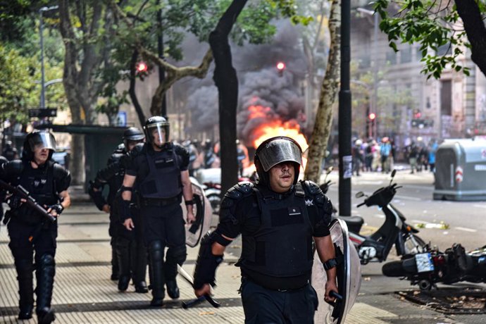 5 de janeiro de 2014, Buenos Aires, Argentina: 12 de março de 2025 - Buenos Aires, Argentina - A infantaria da Polícia Federal avança para limpar a Avenida de Mayo dos tumultos. A fumaça das chamas de um carro de polícia surge ao fundo... Um protesto conj