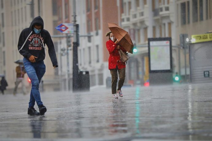 Archivo - Transeúntes caminan por el centro de la capital en una jornada marcada por las lluvias y la bajada de temperaturas, en Madrid, (España).