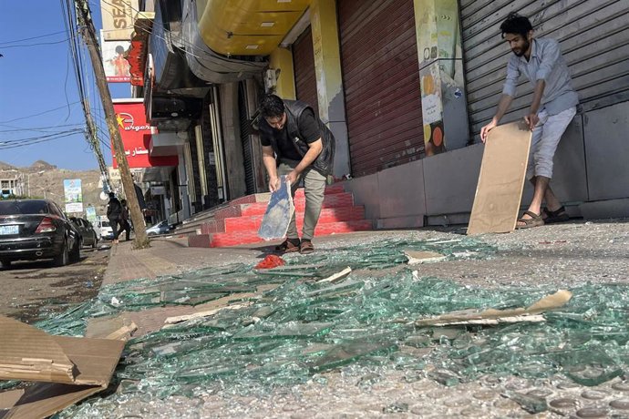 Varias personas recogen escombros en la calle de Saná, Yemen, tras un ataque lanzado por Estados Unidos