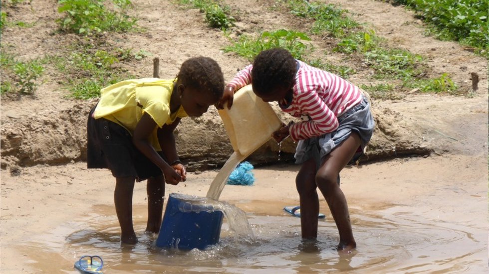 Unas niñas recogiendo agua.