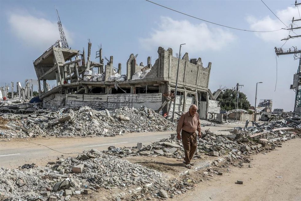 Archivo - Imagen de archivo de un ciudadano palestino frente a un eficio destruido en la ciudad de Deir al Balá, en el centro de la Franja de Gaza