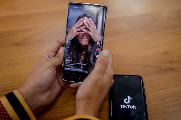 Archivo - Una persona mira en su móvil el vídeo de una joven en la red musical Tik Tok, en Madrid (España), a 22 de septiembre de 2020. TikTok ha publicado este martes su tercer Informe de Transparencia, que recoge la actividad del primer semestre de 2020