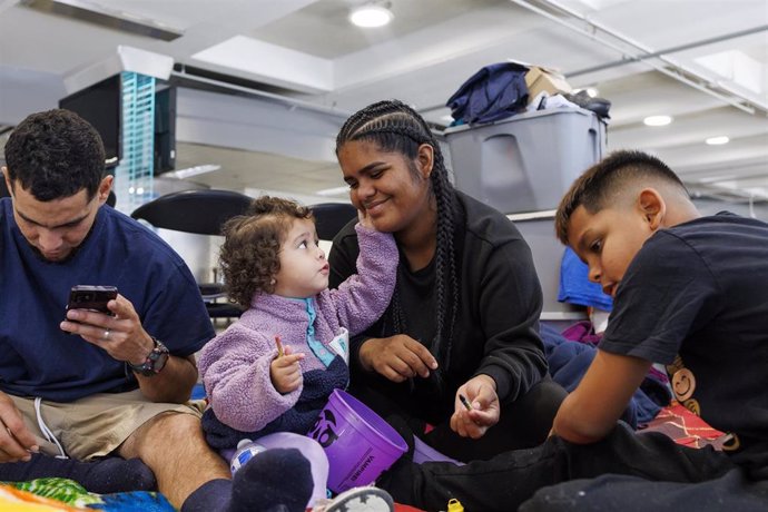 Archivo - December 1, 2024, Chicago, Ill, USA: Luis Daniel, 27, left, and his wife, Maria Cecilia, 28, sit with their children Luisceanny Anthonella, 2, and Luis Angel, 9, all from Venezuela, while the family stays on the floor of a makeshift shelter oper