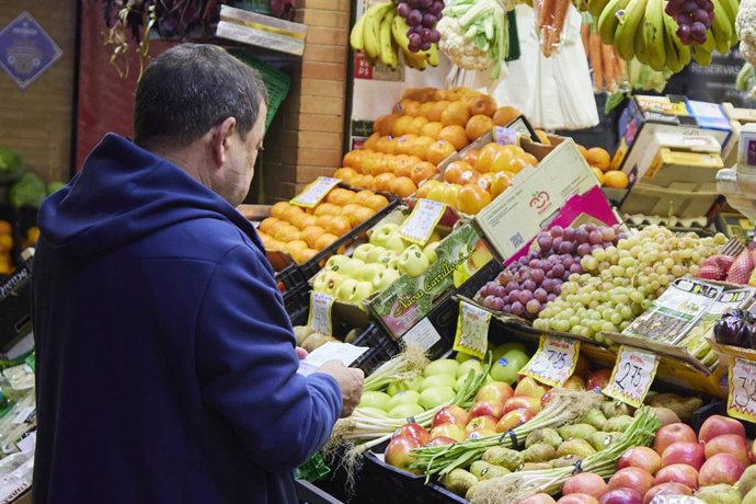 Archivo - Un señor con un listado de productos en un puesto del mercado de abastos