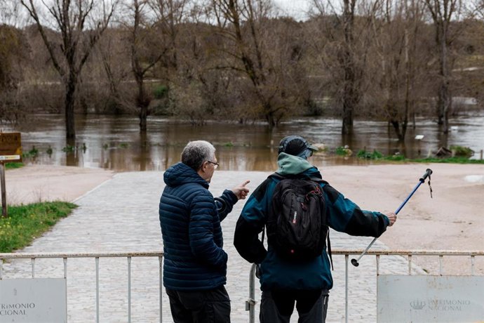 Dos hombres observan el parking de Somontes inundado .