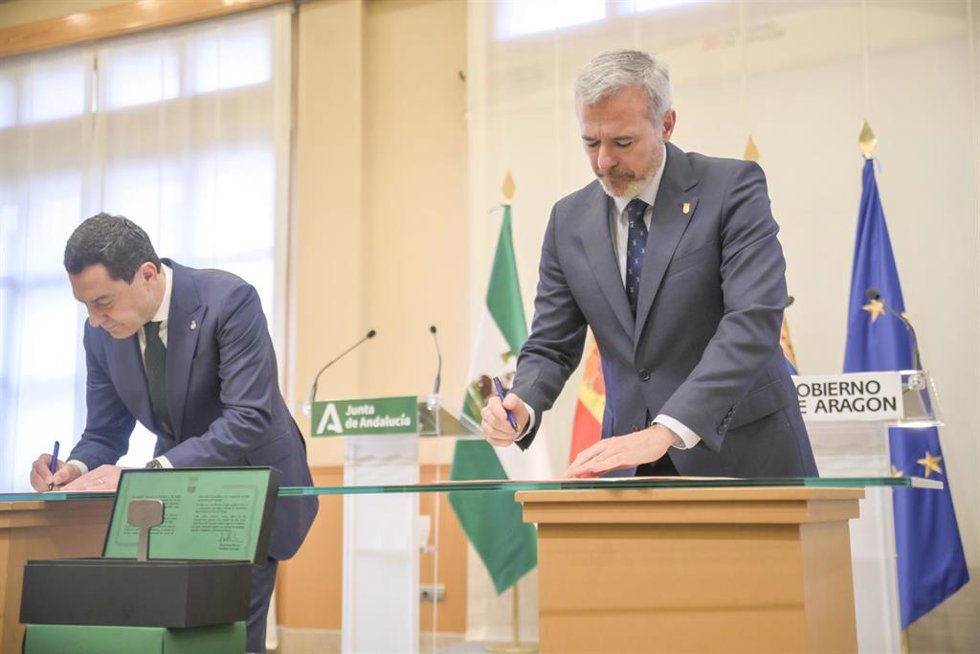 El presidente de la Junta de Andalucía, Juan Manuel Moreno (i) y el presidente del Gobierno de Aragón, Jorge Azcón (d), firman un acuerdo.