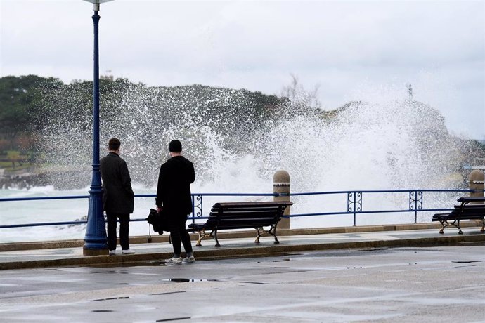 Archivo - Dos personas observan el oleaje en el puerto de Santander