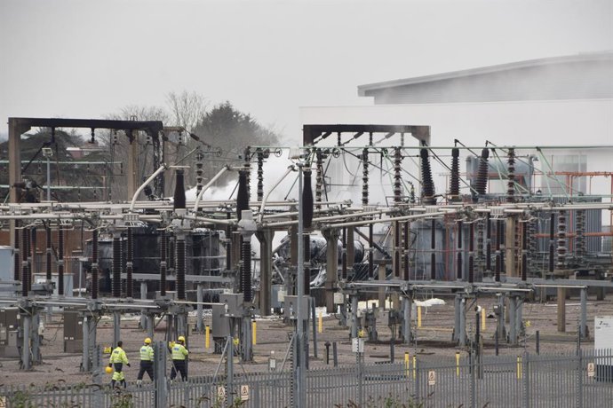 21 de março de 2025, Londres, Reino Unido: O pessoal do serviço de emergência inspeciona a cena enquanto a fumaça se espalha após um incêndio na subestação de eletricidade de North Hyde, em Hayes, causando o fechamento do aeroporto de Heathrow, nas proxim