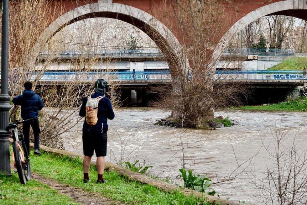 Dos personas observan el río Manzanares a su paso por el puente de los Franceses, a 21 de marzo de 2025, en Madrid (España). El alcalde de Madrid, José Luis Martínez-Almeida, ha asegurado que la ciudad se encuentra en situación de "estabilidad" tras las