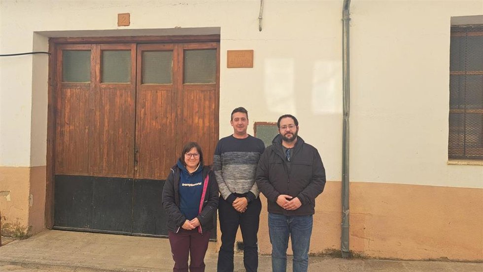 El  alcalde de La Iglesuela del Cid, Fernando Safont, en el centro, flanqueado por los diputados autonómicos Mari Carmen Soler y  Ángel Peralta frente al edificio que se quería reformar para albergar la escuela de Protección Civil.