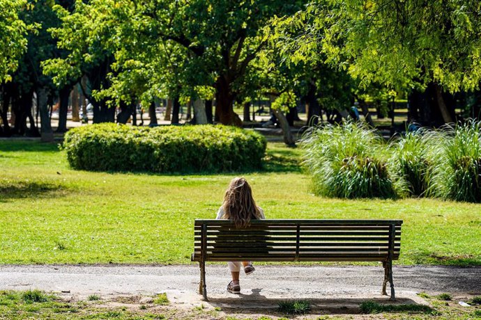 Archivo - Una mujer toma el sol en un banco del Parque de Los Príncipes de Sevilla, en una imagen de archivo.