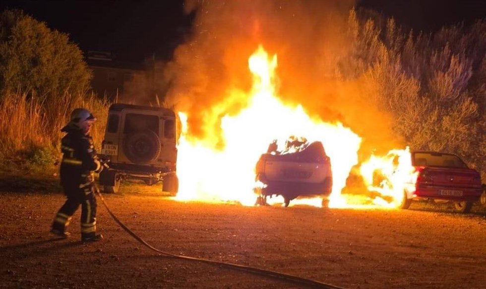 Un bombero sofoca el incendio que ha afectado a 13 vehículos.