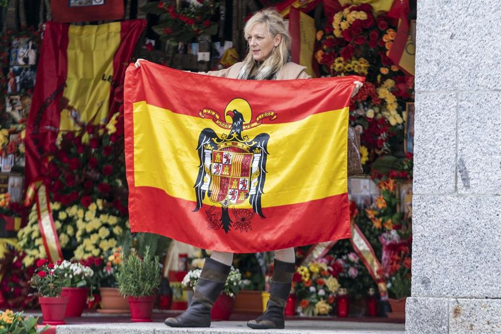 Archivo - Una mujer sostiene una bandera preconstitucional ante el panteón de la familia Franco