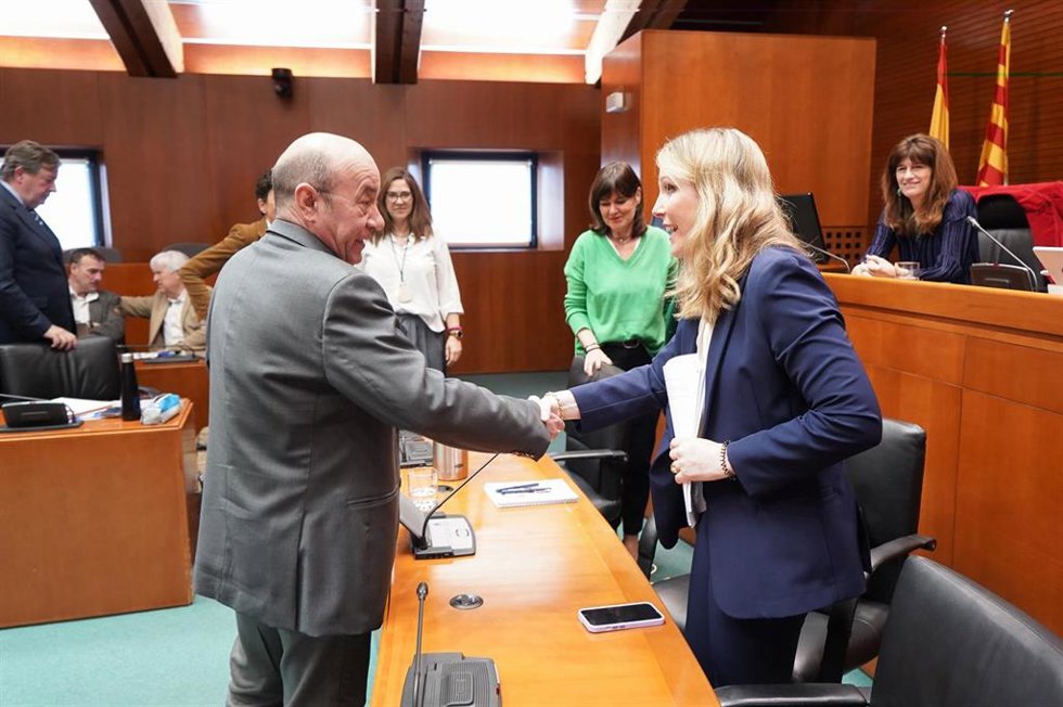 La directora de la oficina del Gobierno de Aragón en Bruselas, María Palacios, saluda al diputado del PSOE Daniel Alastuey antes de comparecer en Comisión de las Cortes de Aragón.