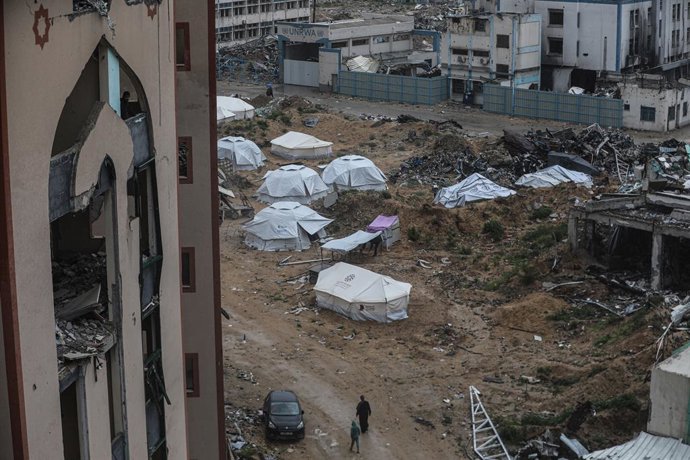 21 de março de 2025, Cidade de Gaza, Faixa de Gaza, Território Palestino: Palestinos deslocados sentam-se em frente a tendas improvisadas montadas entre os prédios destruídos da Universidade Islâmica na Cidade de Gaza em 21 de março de 2025. Israel bombar