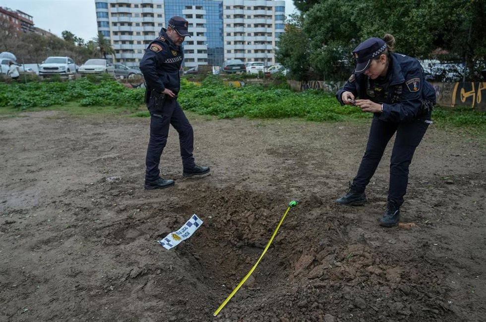 Dos policías toman imágenes y medidas del socavón provocado por un artefacto pirotécnico en un solar de la ciudad de Valncia la pasada semana.  