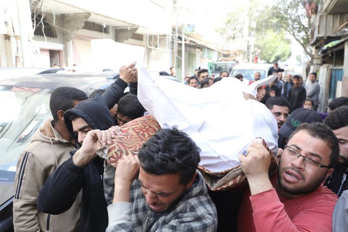 Palestinos trasladan el cuerpo de un muerto en un ataque ejecutado por el Ejército de Israel contra el campamento de refugiados de Bureij, en la Franja de Gaza