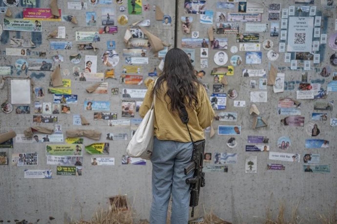 Archivo - Arquivo - Uma mulher em frente a fotografias das vítimas do ataque de 7 de outubro de 2023 ao festival de música Nova durante a comemoração do primeiro aniversário do massacre (arquivo).
