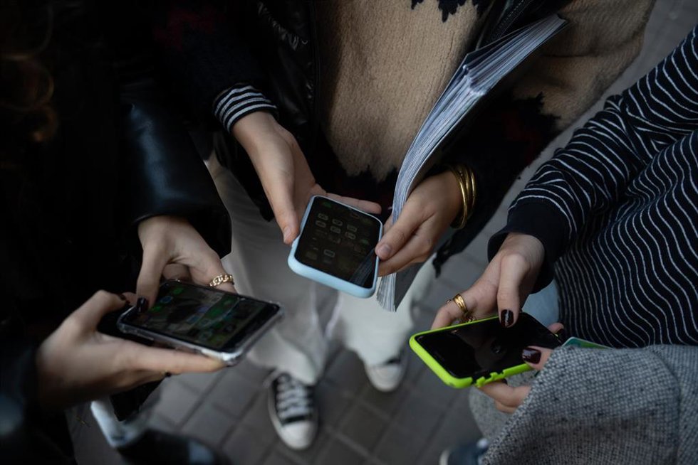 Archivo - Varias personas usan el teléfono móvil