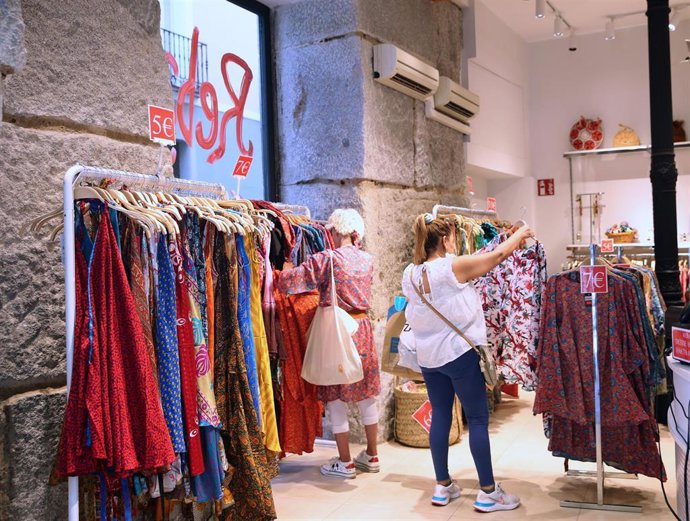 Archivo - Varias personas observan ropa en un establecimiento.