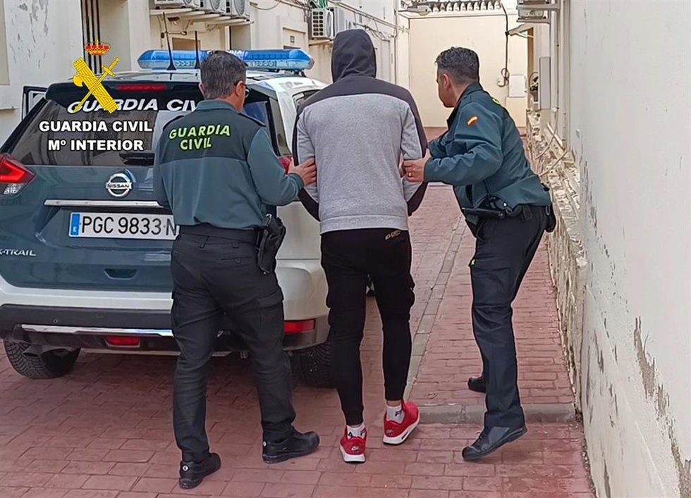 Dos agentes conducen al detenido hasta un vehículo de la Guardia Civil