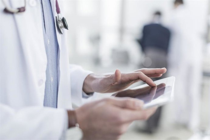 Archivo - Un médico consulta un dispositivo móvil