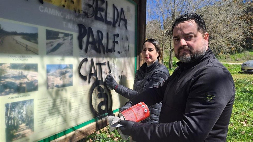 El diputado de VOX en las Cortes de Aragón David Arranz junto a la concejal de la formación en Binéfar, Beatriz Oliván, limpian este domingo 30 de marzo una pintada catalanista en un panel informativo de Albelda (Huesca).