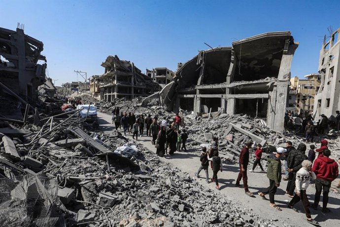 Palestinos ao lado de edifícios destruídos pelo exército israelense na Cidade de Gaza, no norte da Faixa de Gaza.
