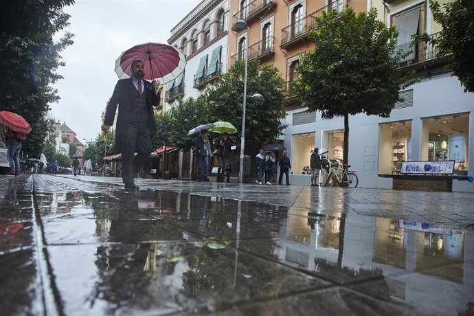 Archivo - Un invitado de una boda pasea por la Calle San Jacinto en un día lluvioso.