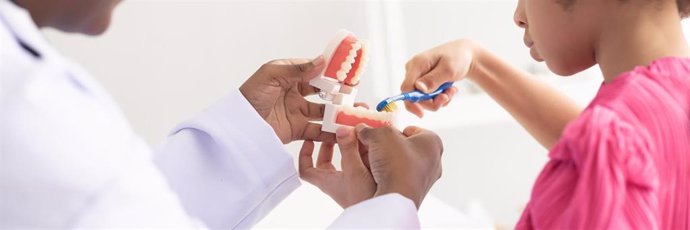 Un niño aprende a cepillar los dientes en la consulta de un dentista.