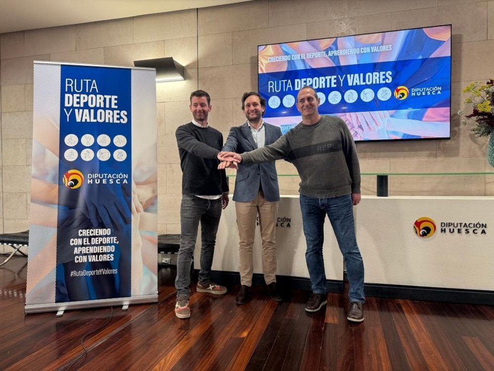 El presidente de la DPH, Isaac Claver, junto al periodista Álex Castresana y el entrenador del Bada Huesca, José Nolasco, en la presentación de la 'Ruta Deporte y Valores' que recorrerá una decena de institutos de la provincia