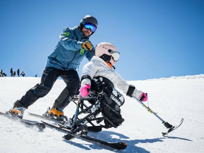 Una participante disfruta del esquí adaptado ayudada por un técnico de la Fundación También