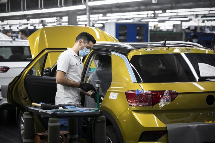 Archivo - 13 May 2020, Portugal, Palmela: An employee wearing a face mask works on the assembly line on a Volkswagen T-Roc in the Portuguese car factory of Volkswagen Autoeuropa. The plant resumed production after one and a half months of production being
