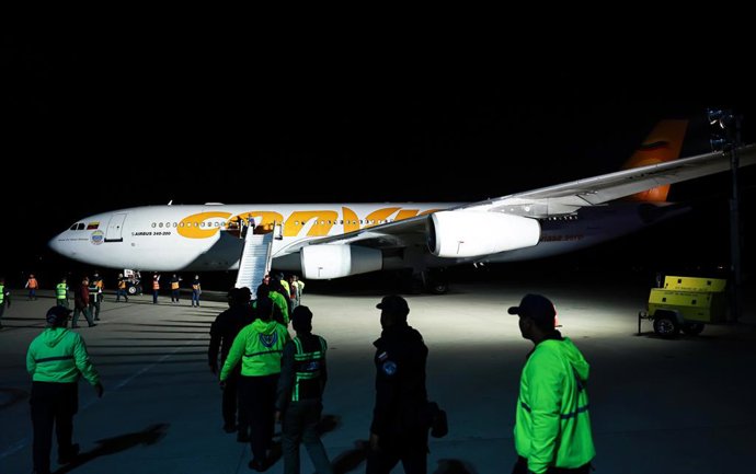 28 de março de 2025, Venezuela, Maiquetia: As forças de segurança ficam em frente ao avião que transporta venezuelanos deportados dos EUA em um voo de repatriação que chega ao Aeroporto Internacional Simon Bolivar. As repatriações fazem parte de um acordo