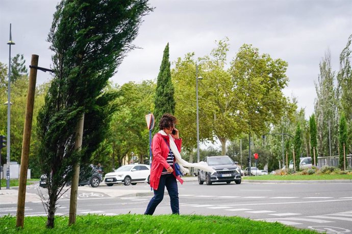 Archivo - Una mujer camina por la calle con aviso por rachas intensas de viento
