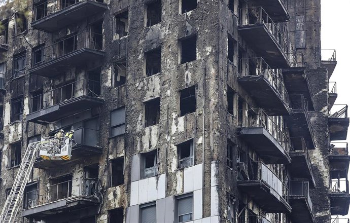 Archivo - Bomberos en una grúa sanean la fachada quemada, a 26 de febrero de 2024, en Valencia