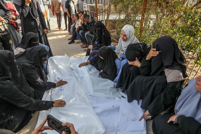 Mulheres palestinas ao lado de várias pessoas mortas em um bombardeio do exército israelense em Khan Younis, no sul da Faixa de Gaza.