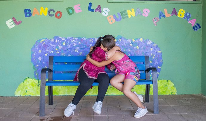 Archivo - Dos alumnas se abrazan en el "banco de las buenas palabras", iniciativa en un centro educativo andaluz contra el acoso escolar.